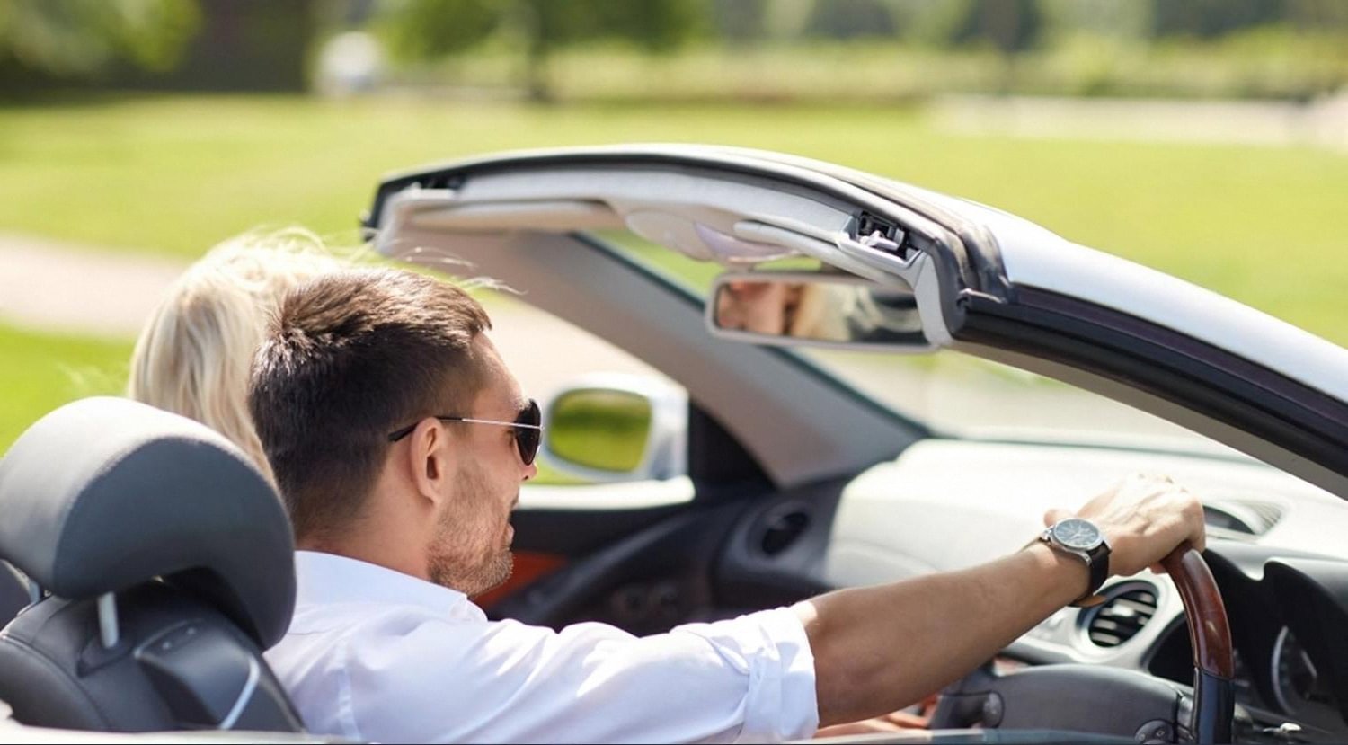 Couple driving a convertible in bright UAE summer sunshine